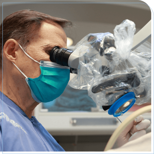 Doctor Scott looking into a microscope while performing root canal surgery