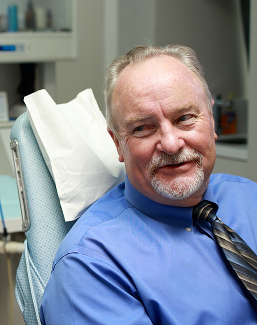 Man in dental chair smiling at his endodontist after cracked tooth treatment