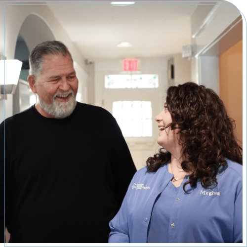 Man walking down hallway while talking with dental team member