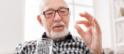 Man holding a pill and a glass of water