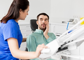 Patient with hurting tooth speaking to emergency dentist