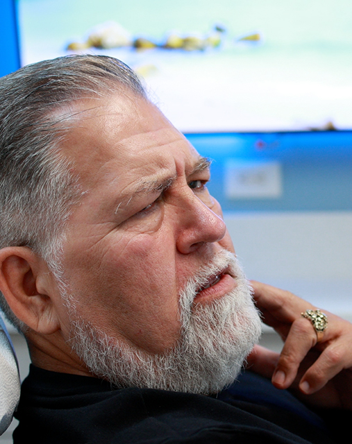 Man holding his cheek in pain while talking to his emergency dentist in Melbourne