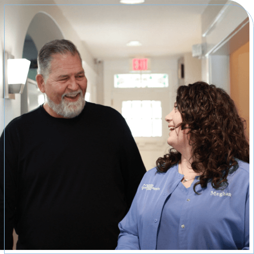 Man walking down hallway while talking to dental team member