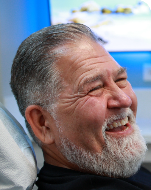 Man in dental chair smiling before root canal treatment with Gentle Wave technology