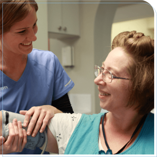 Dental team member smiling while putting a blood pressure cuff on a patient